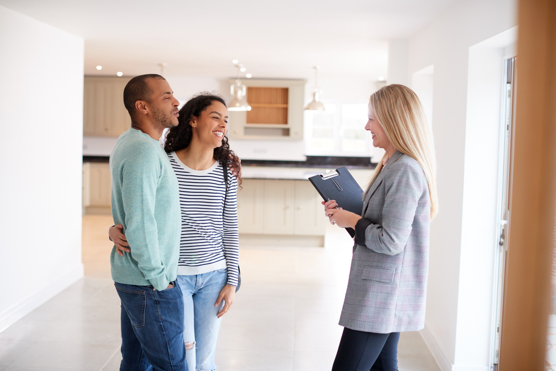 Female Realtor Showing Couple Interested in Buying around House